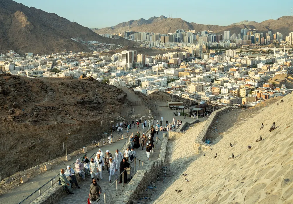 Pilgrims walking along a hillside path above the city