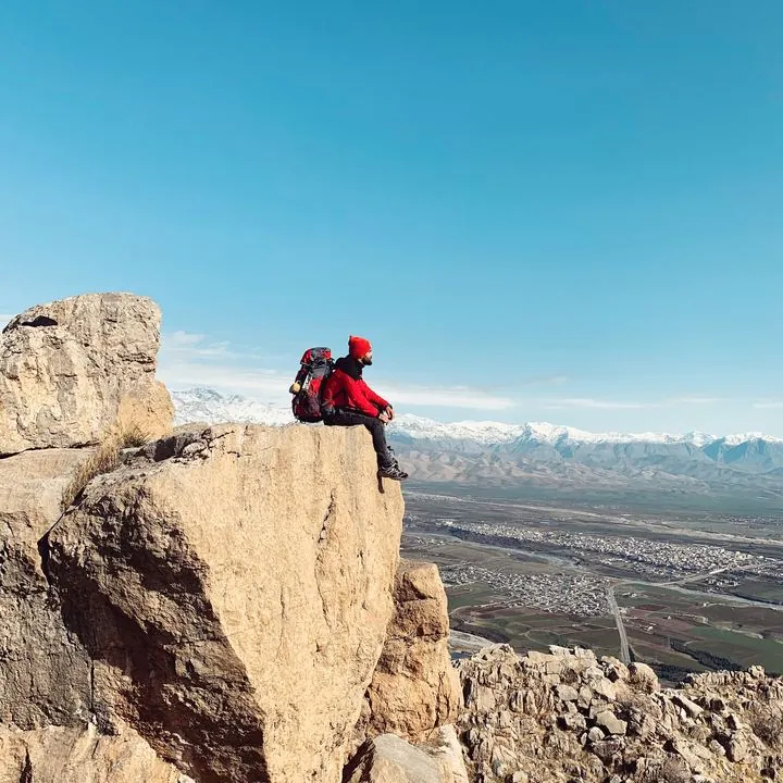 Hiker resting on a clifftop above a valley