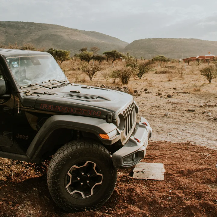 Off-road vehicle parked in dry bush country below the hills